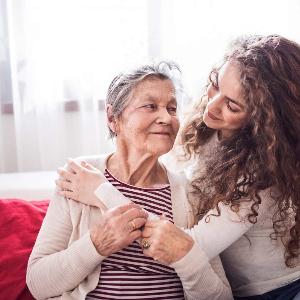 Dona jove i afectuosa feliç i somriure abraçant una dona gran